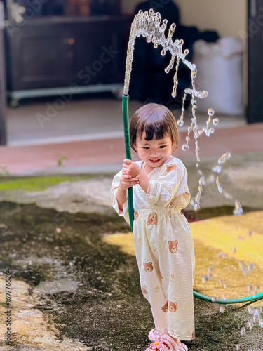 Girl outdoor activity. Children playing water outdoor with happiness in pajamas on sunny day 