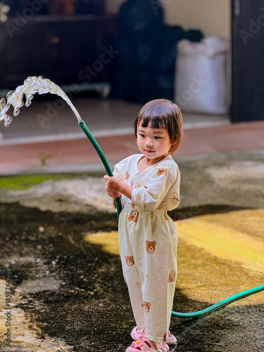 Girl outdoor activity. Children playing water outdoor with happiness in pajamas on sunny day 