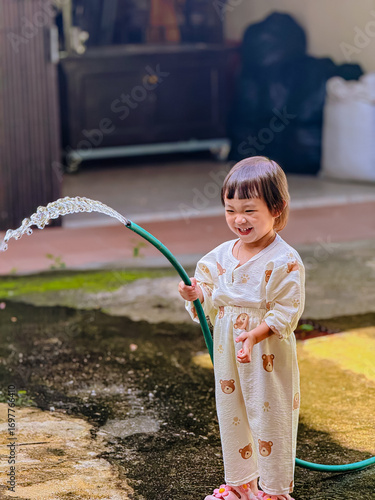 Girl outdoor activity. Children playing water outdoor with happiness in pajamas on sunny day 