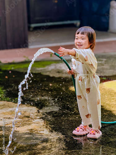 Girl outdoor activity. Children playing water outdoor with happiness in pajamas on sunny day 