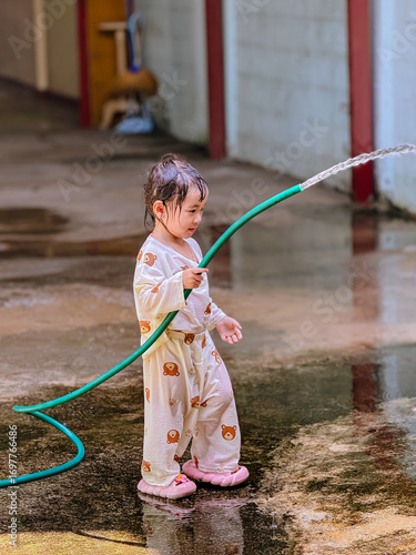 Girl outdoor activity. Children playing water outdoor with happiness in pajamas on sunny day 