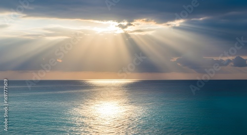 Awe-inspiring crepuscular rays of sunlight break through clouds and illuminate the calm ocean surface. 