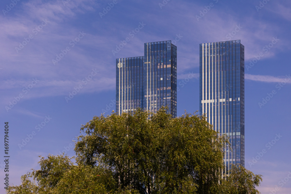 Fototapeta premium High-rise buildings and skyscrapers on a sunny summer day. Sunbeams and glare on the buildings