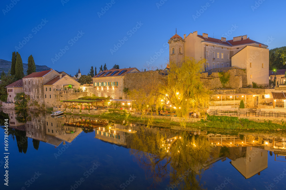 Fototapeta premium Charming Trebinje waterfront at dusk reflecting warm lights and iconic architecture
