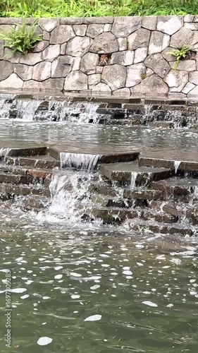Water flowing over rocks in the park. Small cascade of waterfalls outdoors