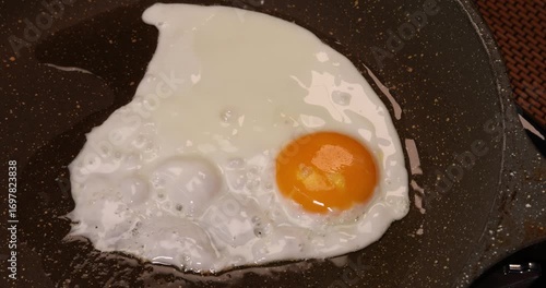 Cooking frying chicken egg sunny side yellow yolk white up in hot oil sizzling