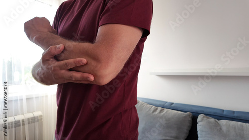 Photos Man with elbow pain at home.