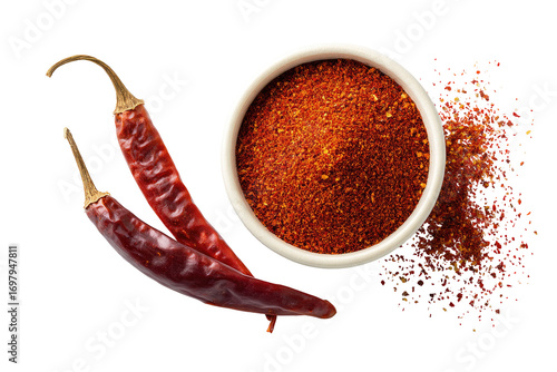 Two chili peppers beside a bowl of red chili powder