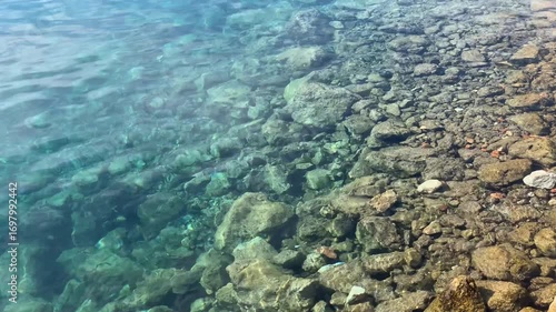 Wallpaper Mural Clear turquoise water gently washing over rocky shoreline, creating serene and natural background Torontodigital.ca