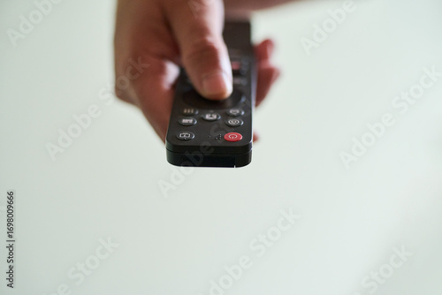 Hand holding a remote control indoors