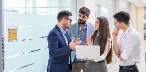 Canvas Print Business people standing in office hallway discussing report during impromptu me