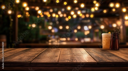 Wooden table with drinks in front of a blurred outdoor bar at night