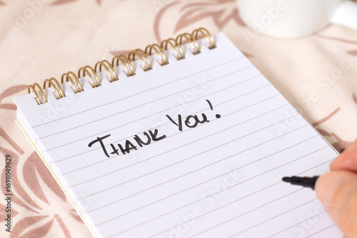Hand writing Thank You quote in notebook with cup of coffee. Close-up. Christian thanksgiving and gratitude concept.