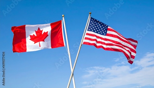 Two national flags, the Canadian and American flags, wave against a clear, light blue sky.