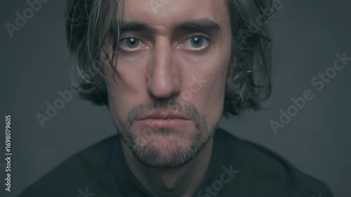 Screaming, shouting, and yelling young Caucasian man with Slavic features expresses varying emotions from calm to intense anger and bewilderment in a neutral setting with muted colors