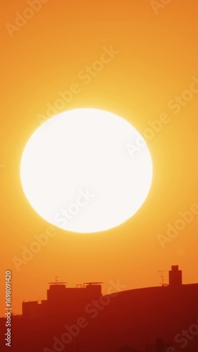 Big sun and a view of the rooftops of the city. Vertical. Timelapse