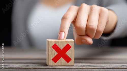 Hand poised to press red x on wooden block with a focused determination in a modern workspace