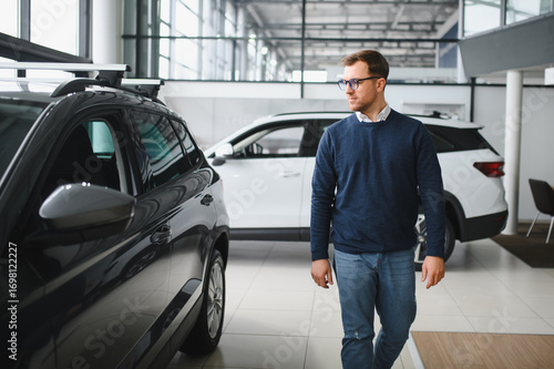 Wallpaper Mural Young man is choosing a new vehicle in car dealership Torontodigital.ca