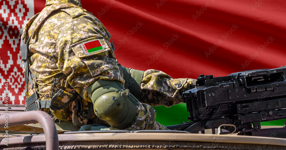 Fototapeta premium Belarus flag with soldier at machine gun turret in front of it. Closeup side view.