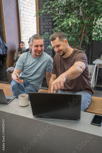 Startup, meeting and team happy in funny, comic and joke time at work with diversity. Office, business and friends together in teamwork with notebook, laptop and coffee workplace