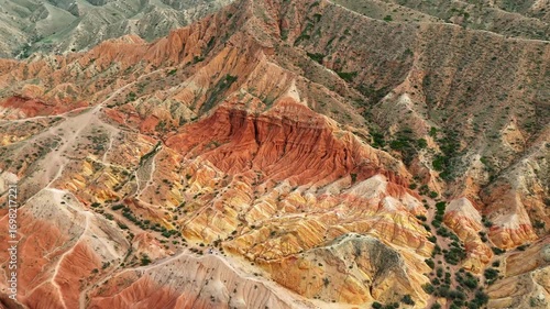 Aerial drone flight above Skazka Canyon in Kyrgyzstan with gradual upward motion, revealing a breathtaking view of the mountain ridge and dramatic red formations.