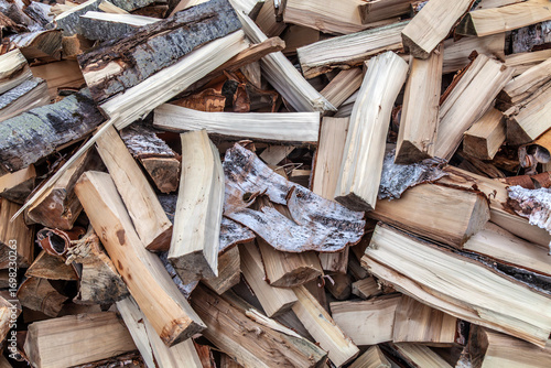 Closeup of an chopped firewood, scattered pile in sunny day.