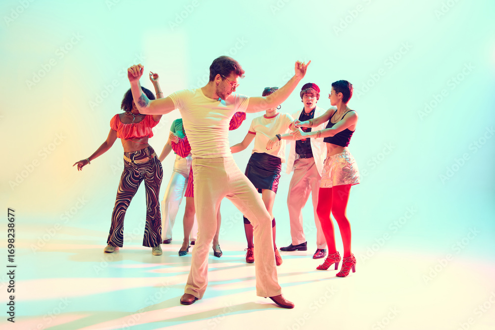 Naklejka premium Friends dancing in group celebration with retro outfits and bright lights. Concept of youth culture, parties, music events and joyful entertainment.