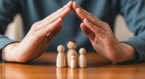 Hands forming roof over wooden family figurines on a polished wooden surface top