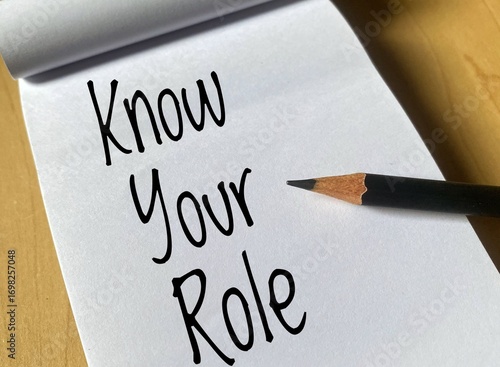 Written word Know Your Role on white paper against wood background. 