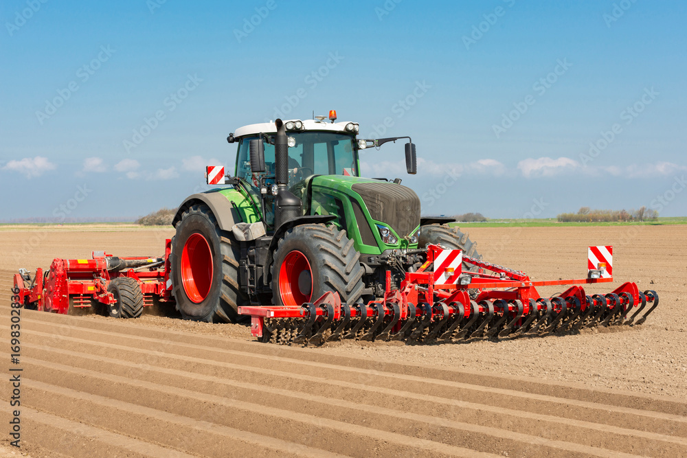 Obraz premium Tractor with front tiller and rotary hiller forming ridges for potato cultivation in the field - 1060