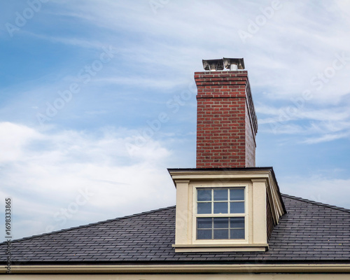 Elegant dormer window and prominent brick chimney on a home's roofline in Boston, Massachusetts, USA
