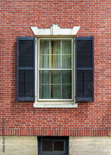 Historic red brick wall featuring decorative lintel and stone foundation window in Boston, Massachusetts, USA
