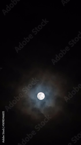 Vertical video - Timelapse of the full moon rising behind the clouds