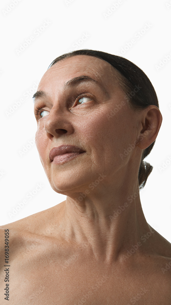 Fototapeta premium Older woman looking upward with calm expression in skincare portrait. Concept of dermatology, medical study, natural beauty, aging process and self-acceptance.