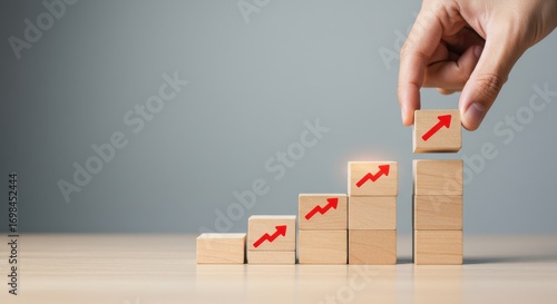 Conceptual image of business growth and progress visualized by wooden blocks stacked in ascending order with upward arrows