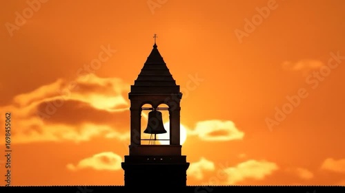Bell Tower Silhouetted against Sunset: The silhouette of a bell tower stands tall against a vibrant sunset sky, capturing the serene and historic charm of the scene.