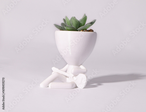 white fliwer pot in a shape of man whith green succulent 