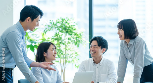 Tapety artystyczne オフィスでノートパソコンを前に笑顔で打ち合わせをする4人の日本人会社員たちのビジネスミーティング