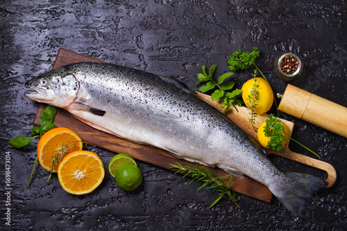 Raw whole salmon fish on black background. View from above, top studio shot