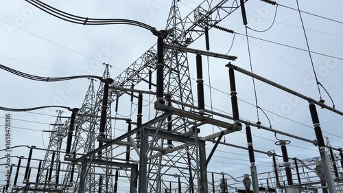 Disconnecting switch substation cloudy sky, high voltage power line and metal tower grid with ceramic insulator structure, industrial energy infrastructure and electricity transmission distribution
