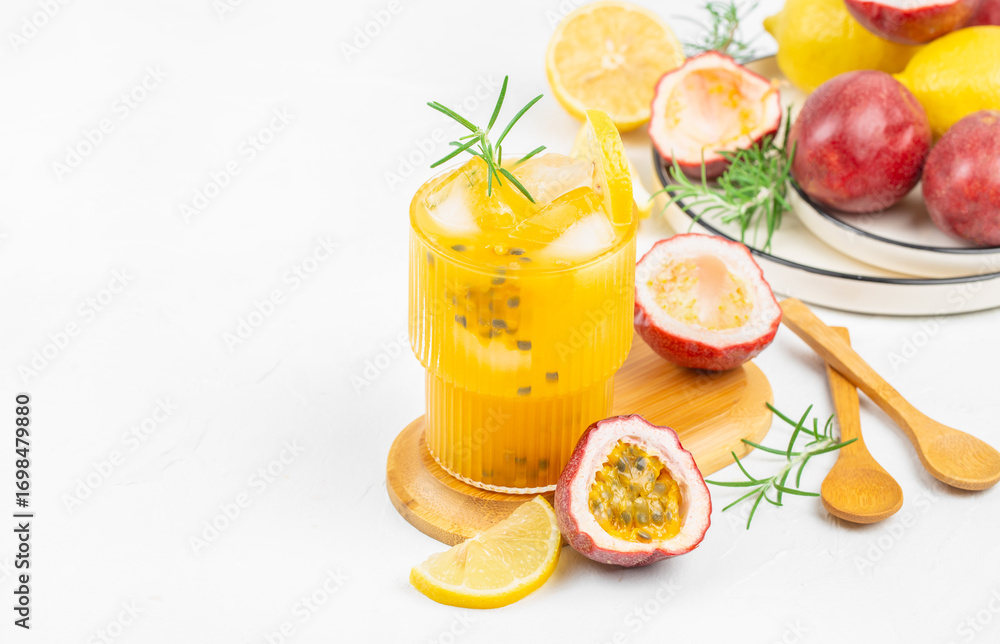 Fototapeta premium Refreshing passion fruit and lemon juice with ice and rosemary on a white background, top view, copy space
