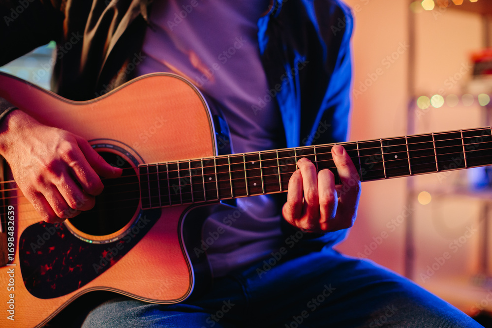 Fototapeta premium Musician playing acoustic guitar and writing music at home
