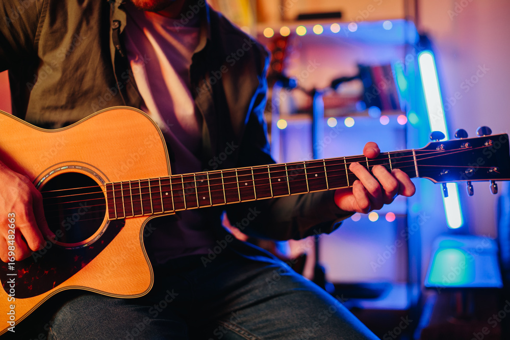 Obraz premium Musician playing acoustic guitar and writing music at home