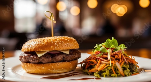 Gourmet beef burger with cheese and red onion, served with a vibrant fresh side salad on a white plate in a warm restaurant setting.