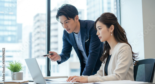 日本人ビジネスパーソンの男女がオフィスで資料を確認する打ち合わせ