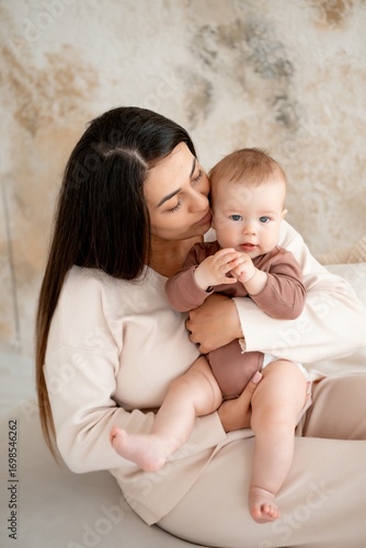 mom and baby, maternal love and care, a mother holds a baby in her arms, gently kissing and hugging him at home, a mother with a small child on maternity leave
