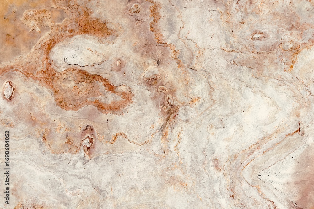 Fototapeta premium Natural stone texture with earthy tones of gray and rusty orange, showcasing rough surface patterns and organic details, ideal for backgrounds or design elements.