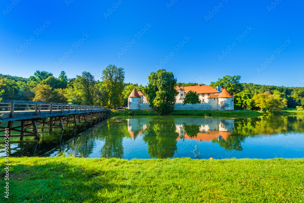 Fototapeta premium Wooden bridge over Krka river and Otocec Castle in Slovenia, popular tourist destination
