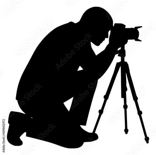 Silhouette of a photographer kneeling with camera on tripod, ready to take a shot