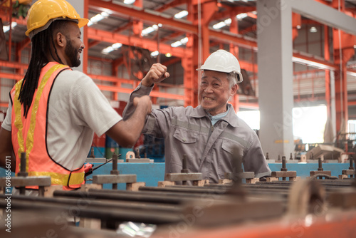 Senior engineers and young man workers are talking and inspecting machines on a production line
